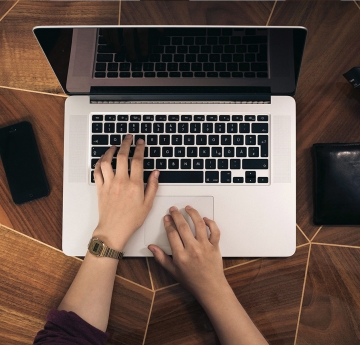 Typing on a laptop on brown table