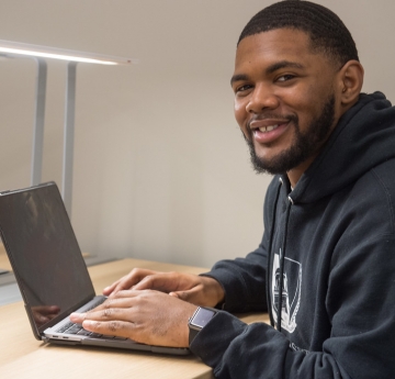 Smiling male student working on a laptop